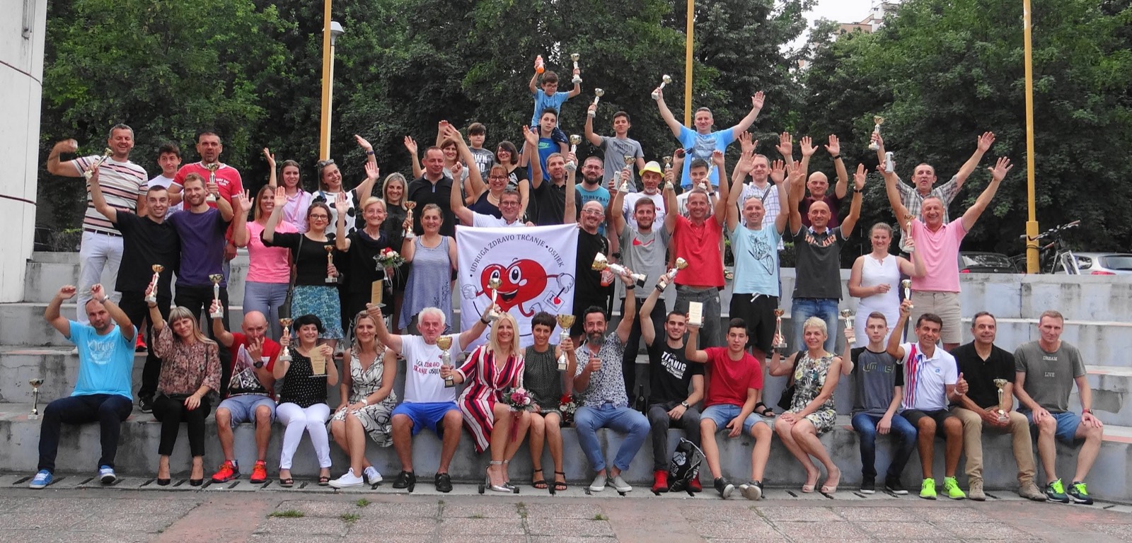 Članovi udruge mašu sa stepenica, sa zastavom udruge